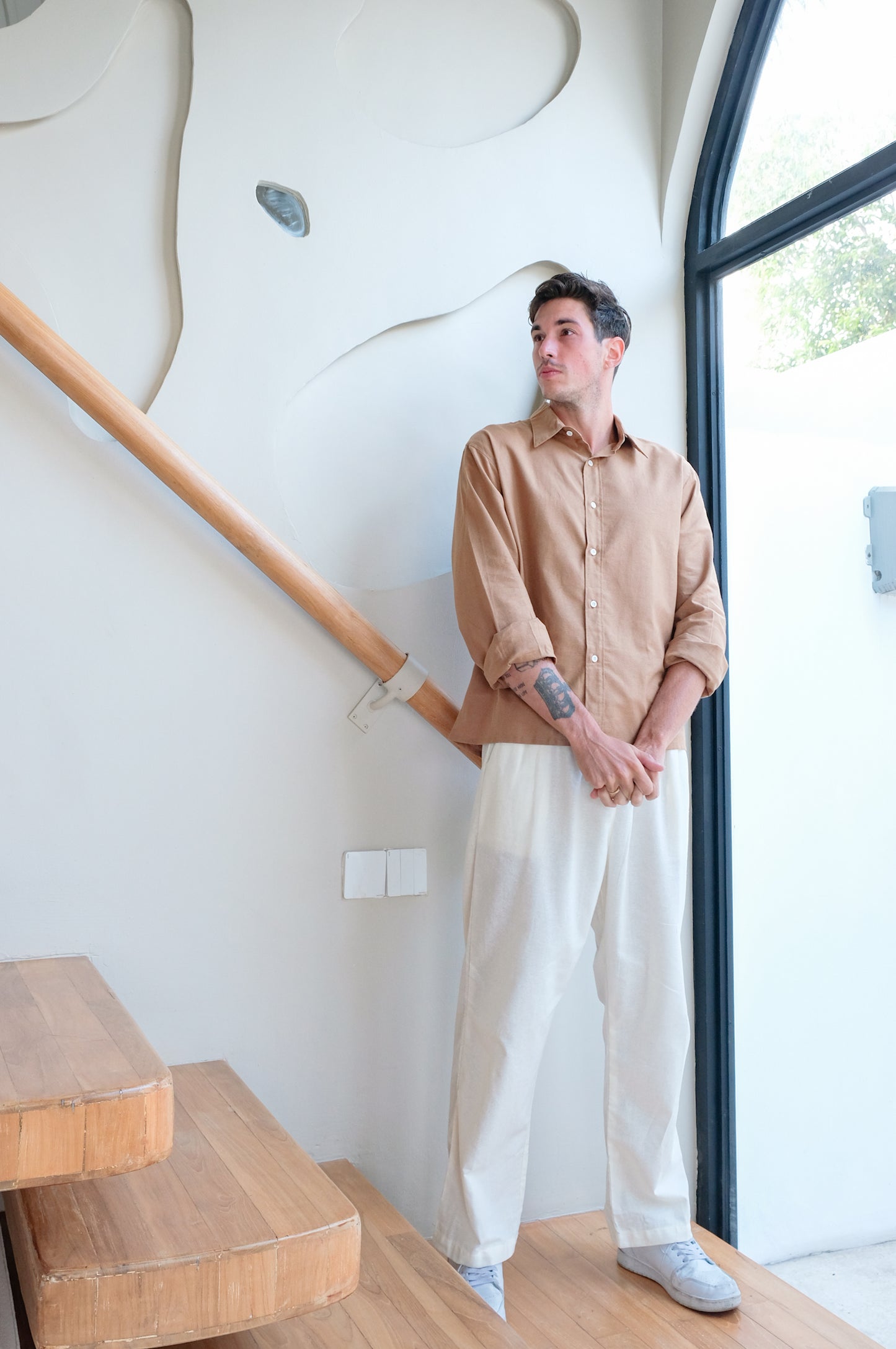 Man waiting in his new brown shirt combined with white trouser all made of linen breathable fabric by Una Linen Havn.