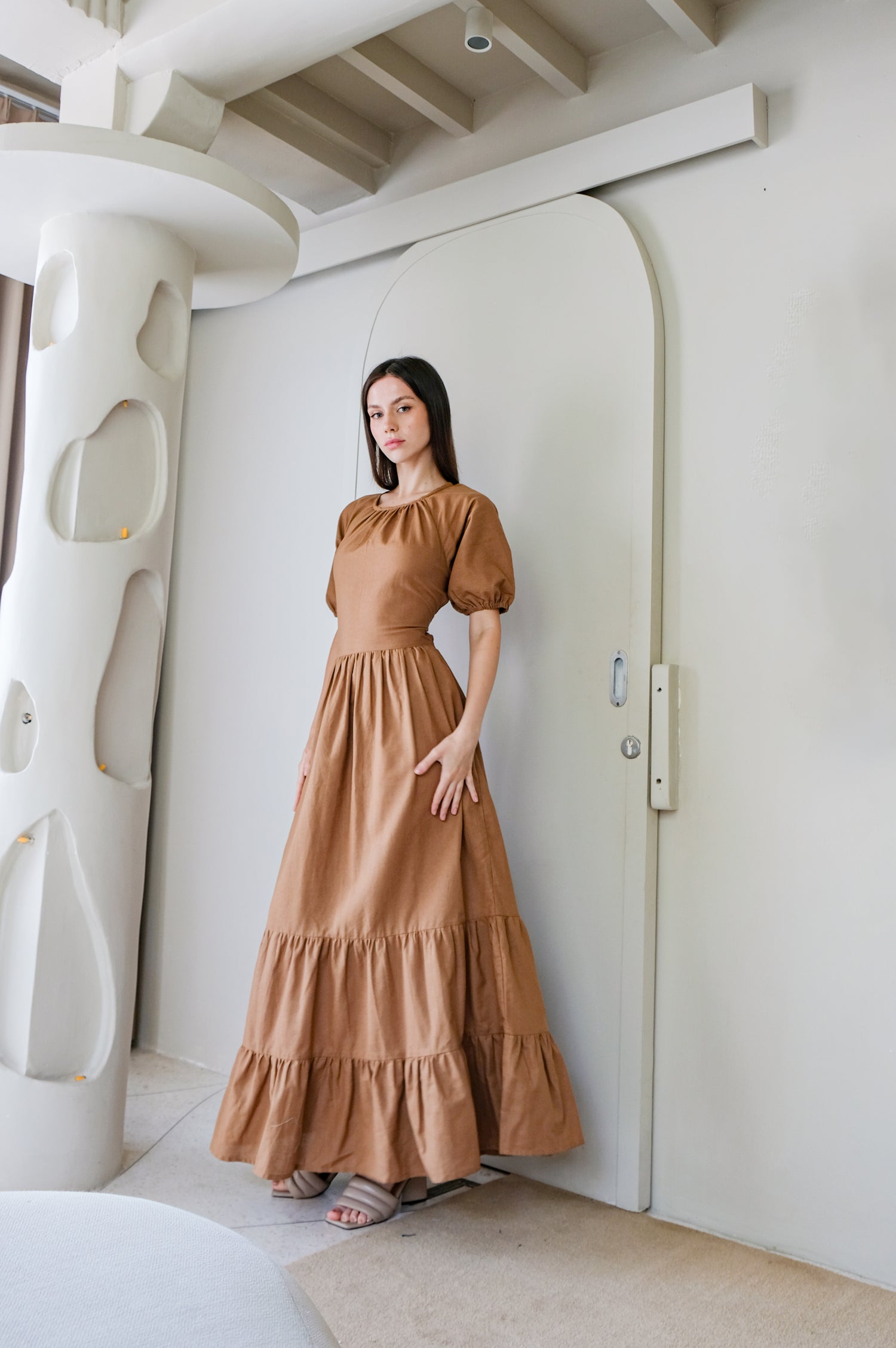 Young woman wearing long linen dress  in brown called Kvilda by Una LInen Havn.