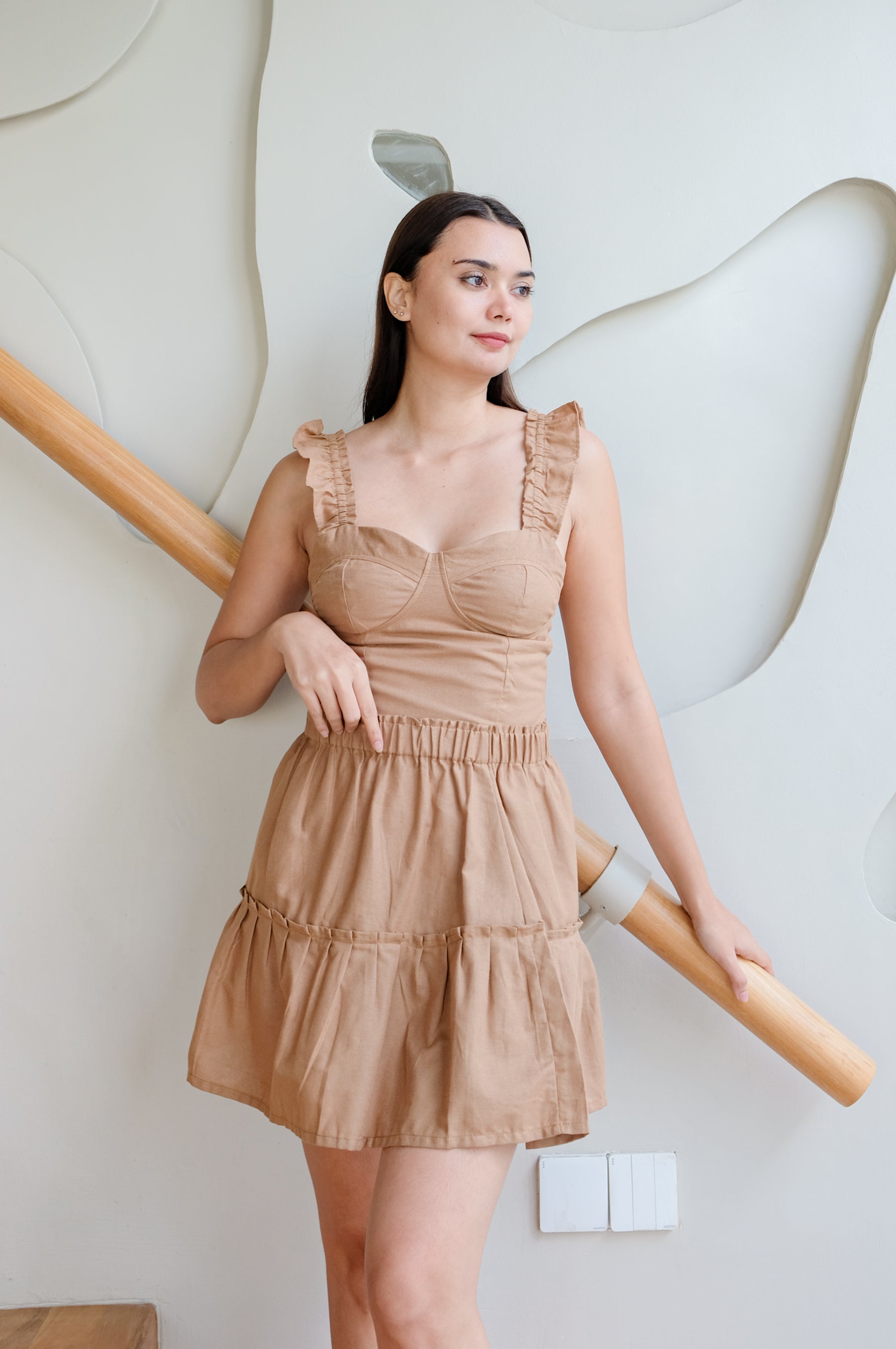 Model posing to display brown set of top and skirt from linen. 