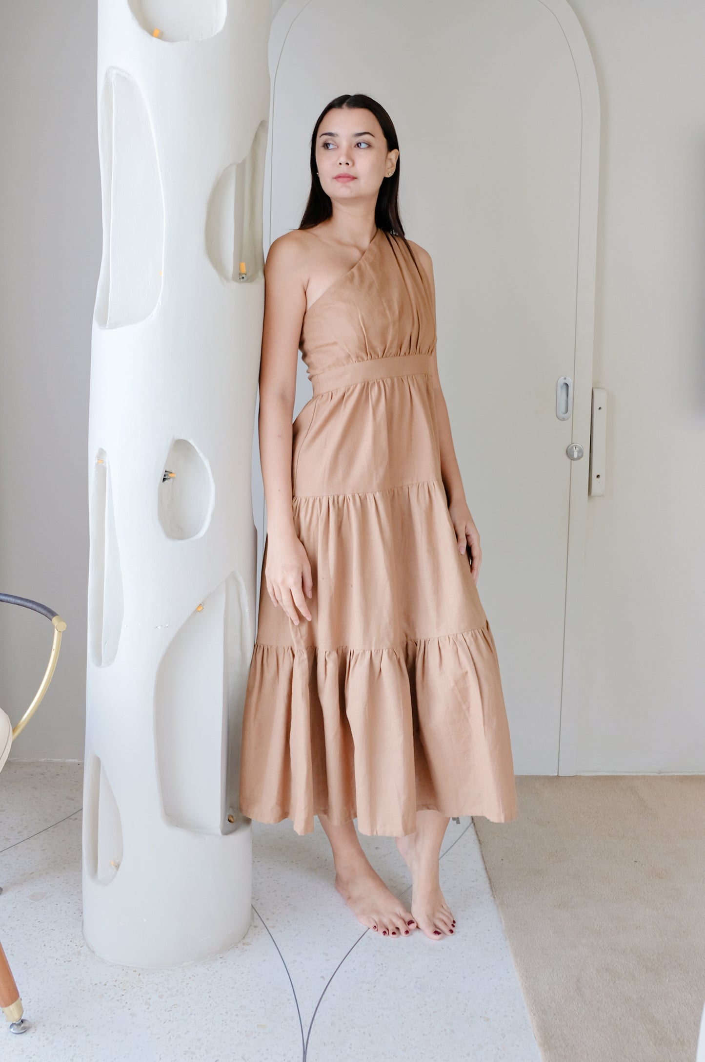 Brown flowy dress made of linen on figure.