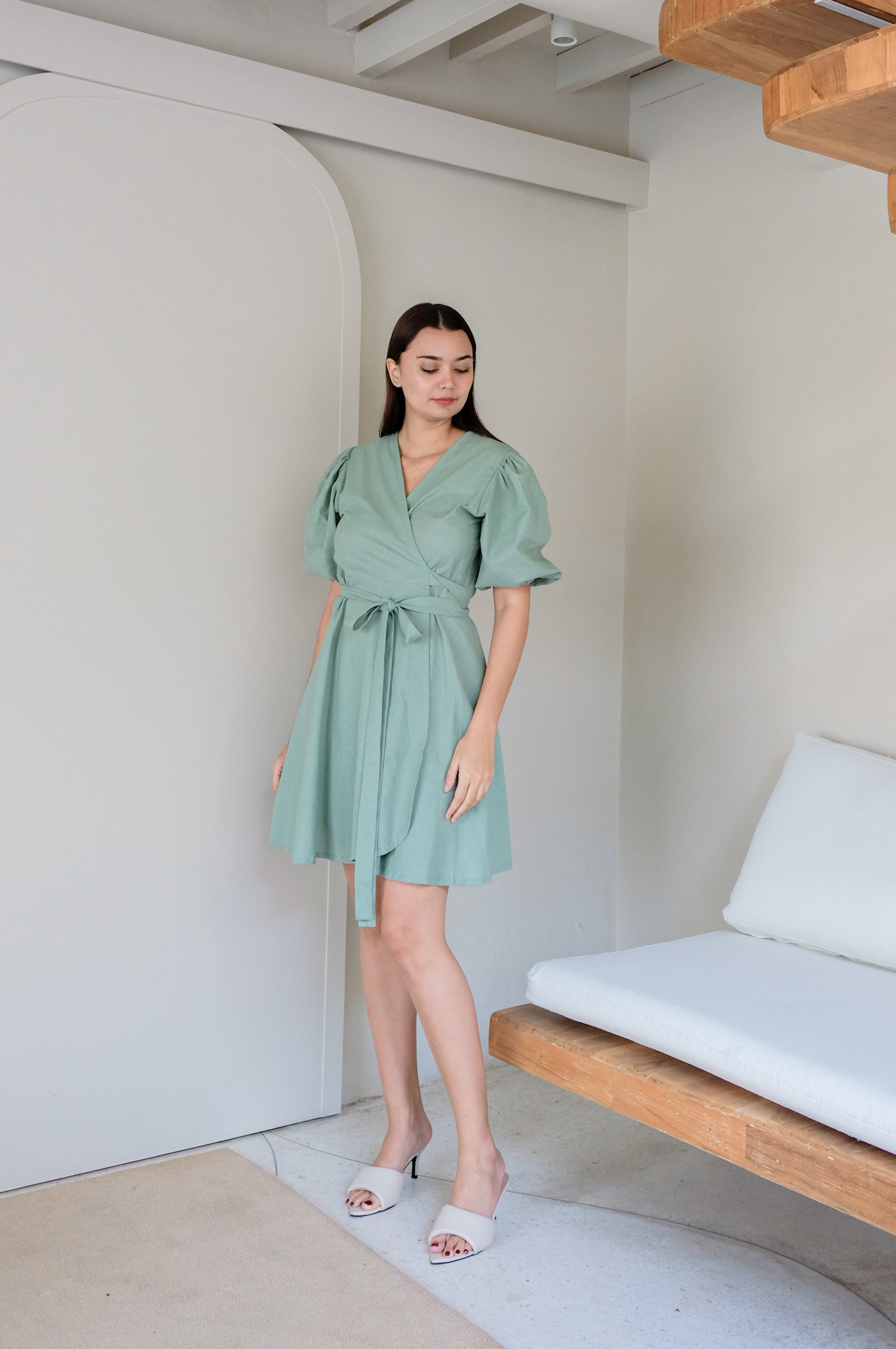 A model showing green linen kimono dress in minimalistic white interior.
