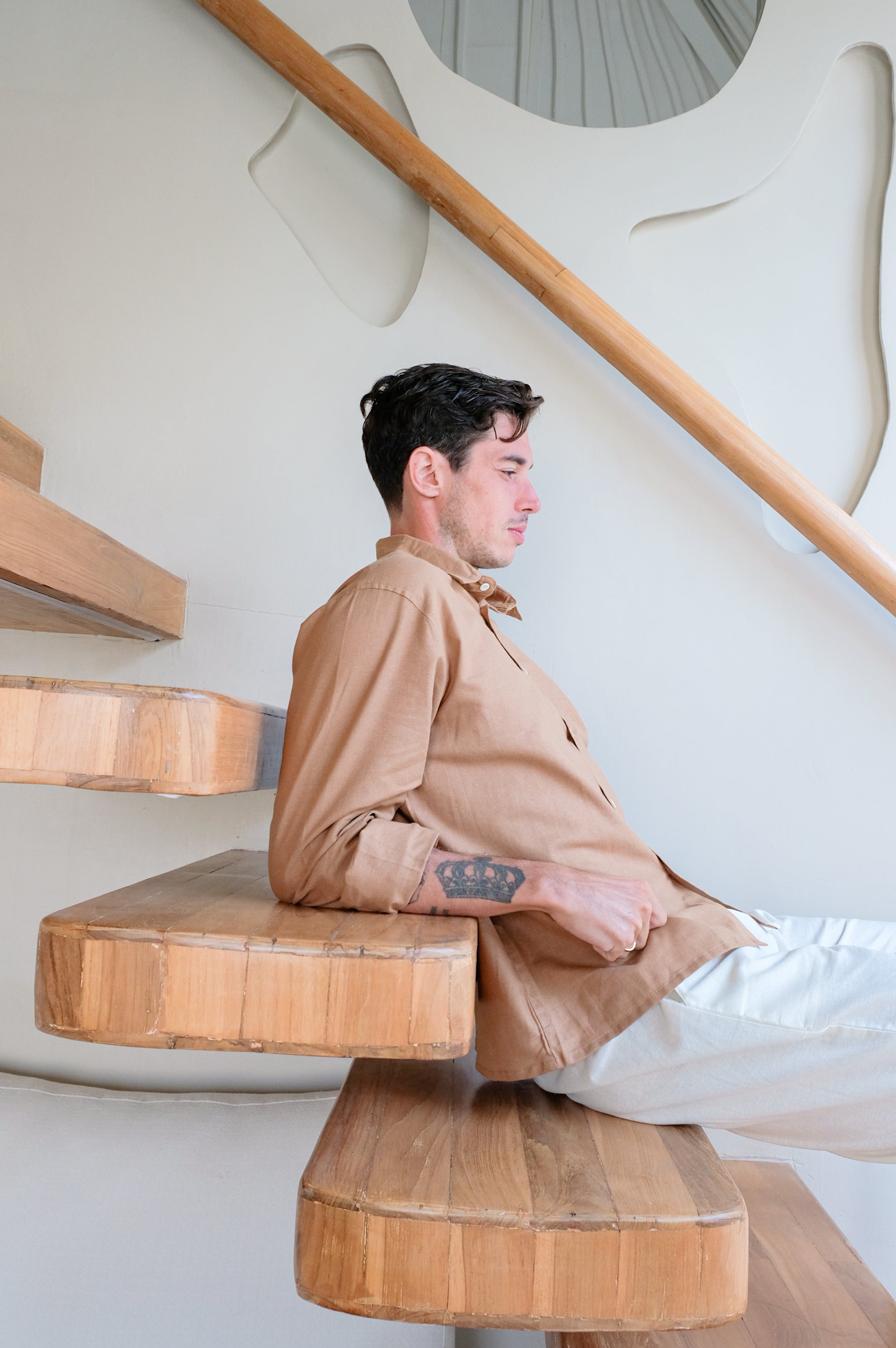 Model sitting on stairs presenting linen shirt and white trousers by Una Linen Havn
