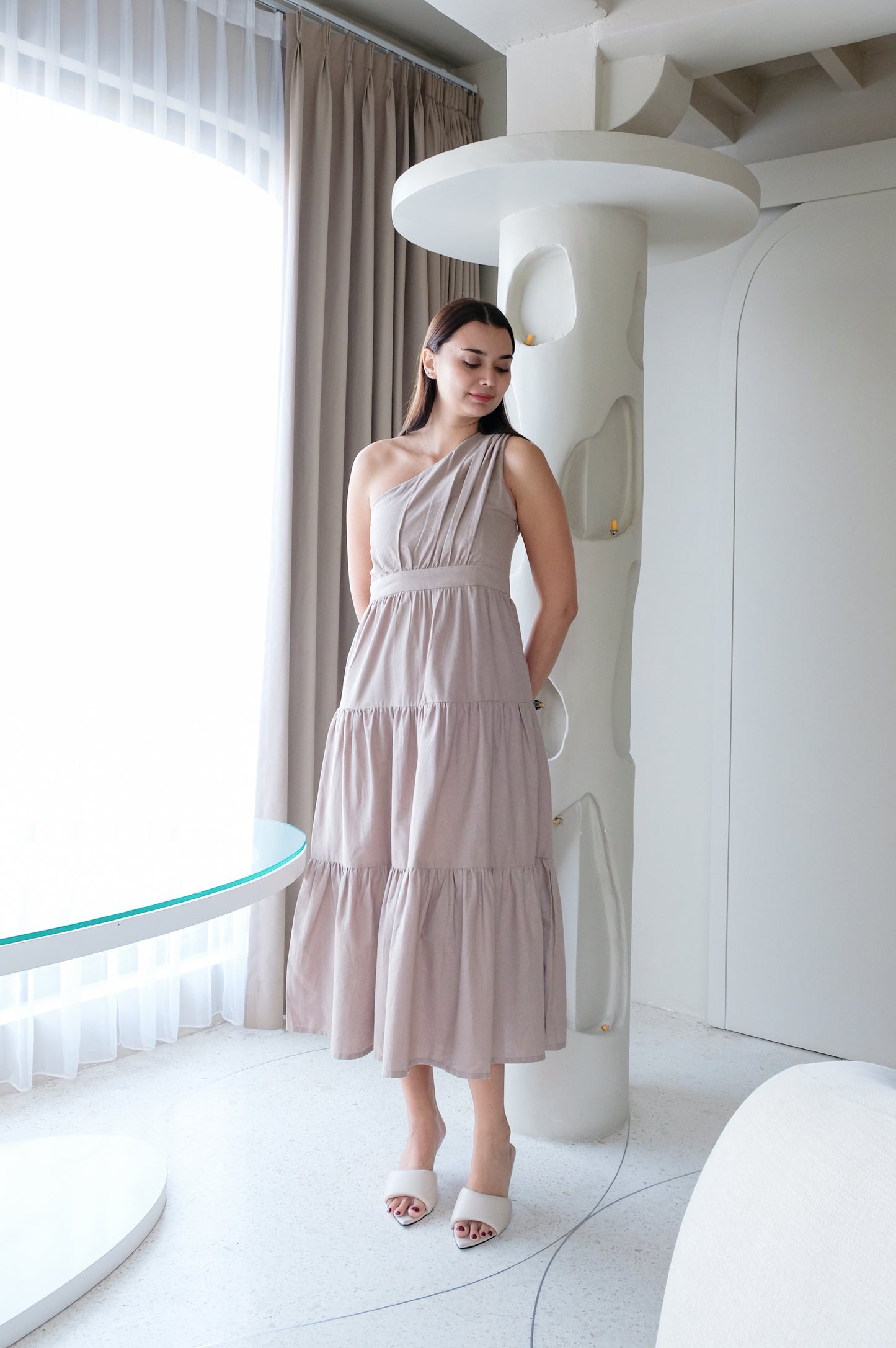 Display of beige linen dress with wide skirt on a model. 